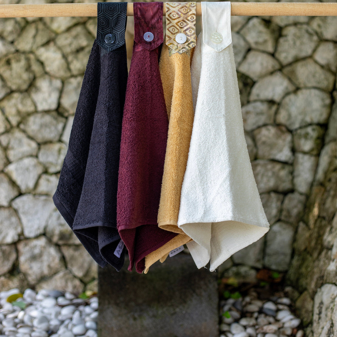 Modern Hanging Hand towels. The whole towel is used with a cotton tab attached to loop over and secure with a modern button. Available in Black, port wine, wheat and off white.