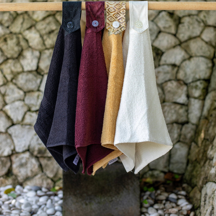 Modern Hanging Hand towels. The whole towel is used with a cotton tab attached to loop over and secure with a modern button. Available in Black, port wine, wheat and off white.