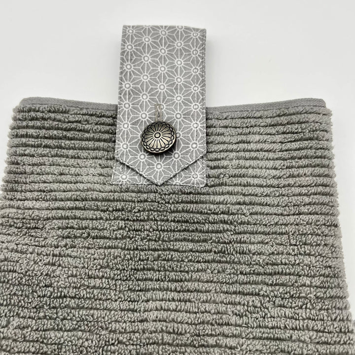 Modern grey ribbed hanging hand towel.  Has a grey fabric strip attached with button closing.   